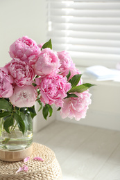 Bouquet of beautiful peonies on pouf indoors