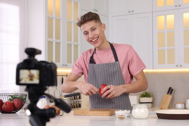 Photo of Smiling food blogger cooking while recording video in kitchen