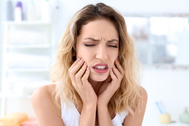 Photo of Young woman suffering from toothache indoors