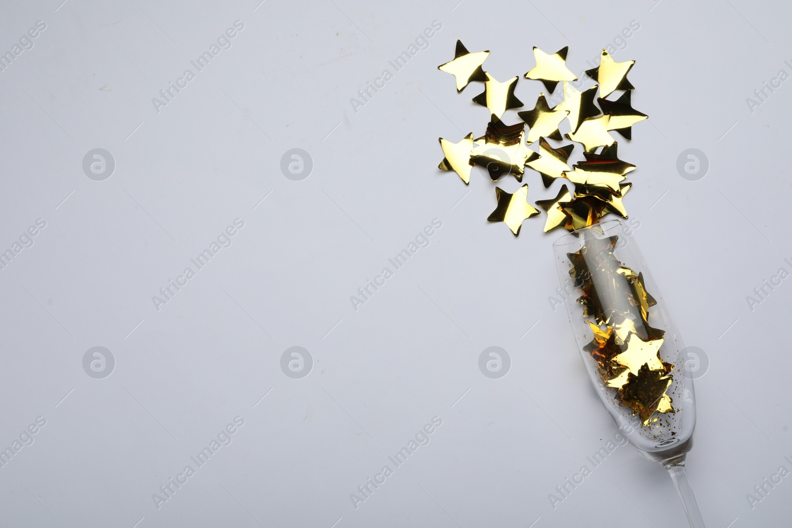 Photo of Flat lay composition with confetti and champagne glass on light background. Space for text