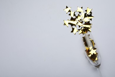 Photo of Flat lay composition with confetti and champagne glass on light background. Space for text