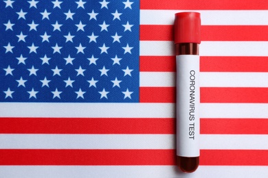 Photo of Test tube with blood sample on American flag, top view. Coronavirus pandemic in USA