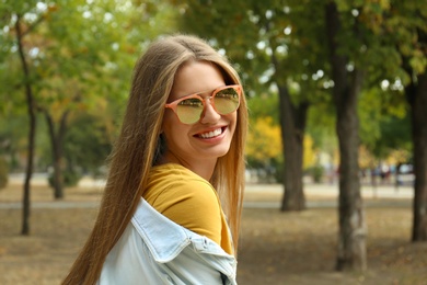 Photo of Young woman wearing stylish sunglasses in park
