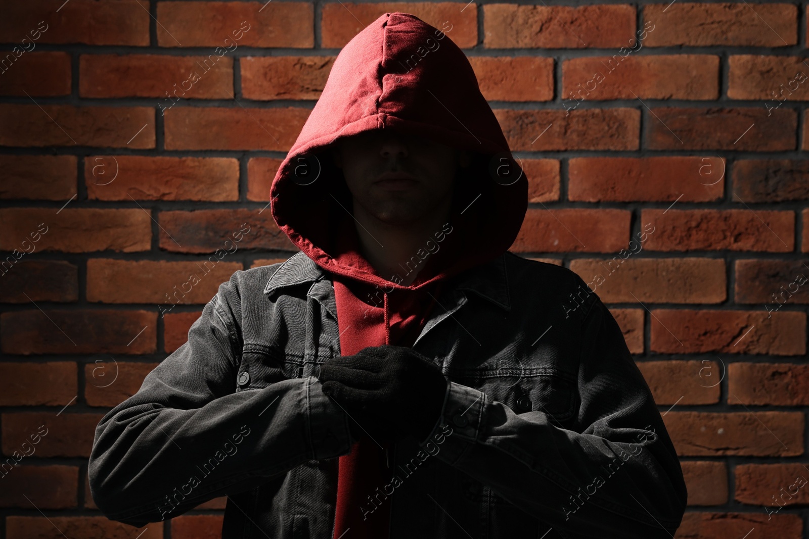 Photo of Thief in hoodie against red brick wall