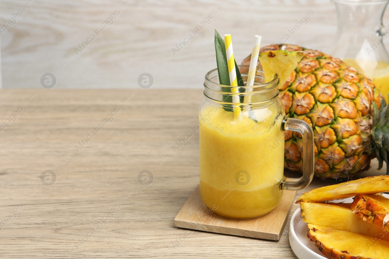 Photo of Tasty pineapple smoothie and fruit on wooden table. Space for text