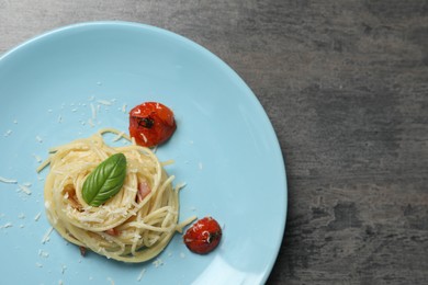 Photo of Tasty spaghetti with tomatoes and cheese on grey table, top view and space for text. Exquisite presentation of pasta dish