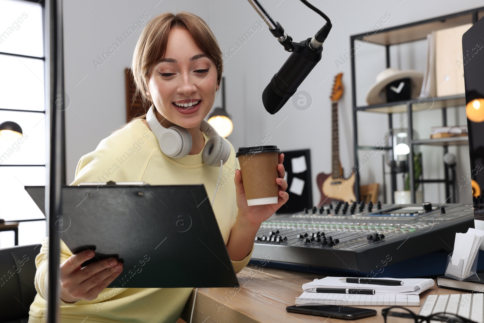 Photo of Woman with cup of coffee working as radio host in modern studio