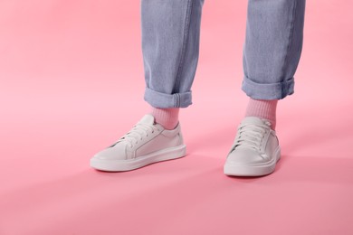 Photo of Woman wearing stylish white sneakers on pink background, closeup