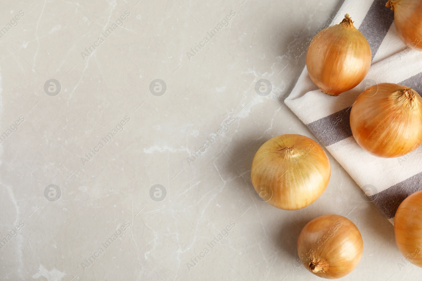 Photo of Ripe onions on grey table, flat lay with space for text