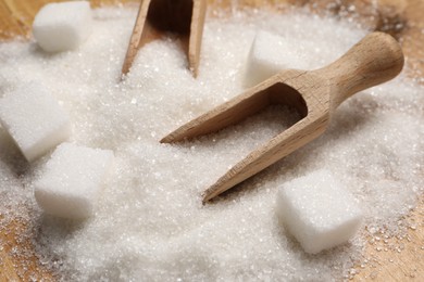 White sugar with scoops on wooden table, closeup
