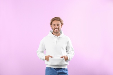 Portrait of man in hoodie sweater on color background. Space for design