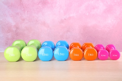 Many dumbbells on table against color background. Fitness equipment