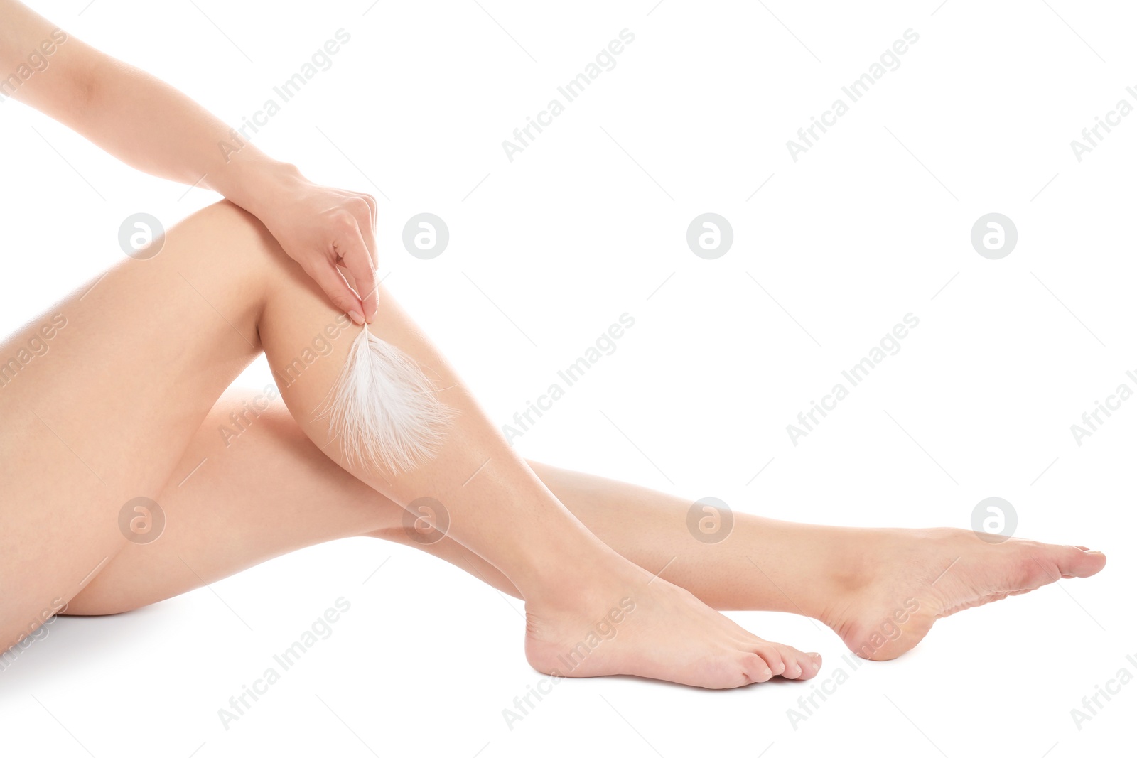 Photo of Woman touching leg with feather isolated on white, closeup. Epilation procedure
