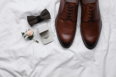 Photo of Flat lay composition with wedding shoes on white fabric, space for text