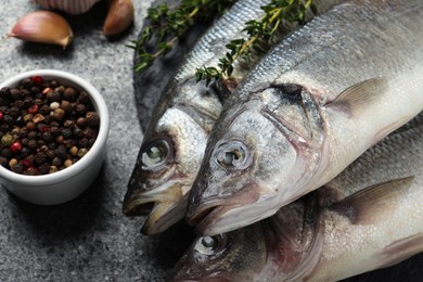 Tasty sea bass fish and spices on dark grey textured table, closeup