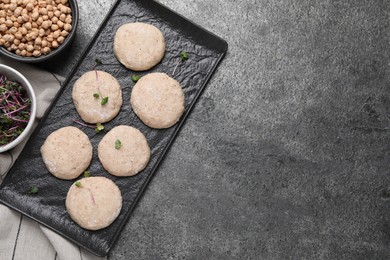 Photo of Raw vegan nuggets, greens and chickpeas on grey table, flat lay. Space for text