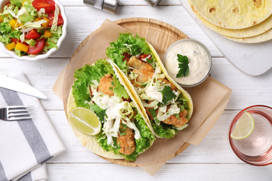 Photo of Yummy fish tacos served on white wooden table, flat lay