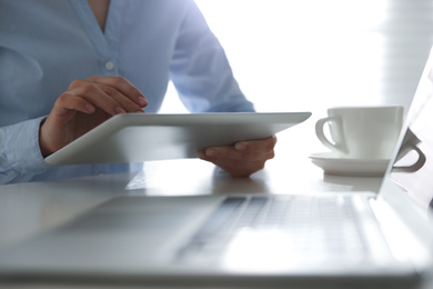 Photo of Businesswoman working with modern tablet at table in office, closeup