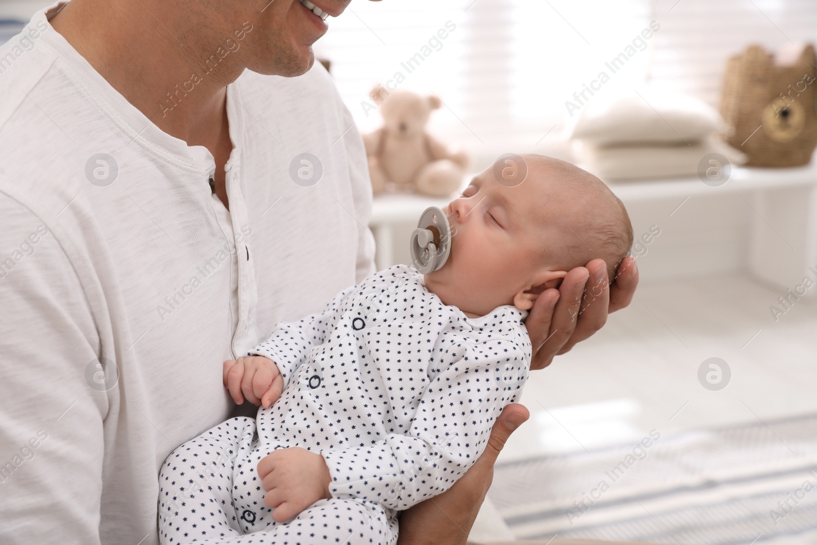 Photo of Happy father with his cute sleeping baby at home, closeup