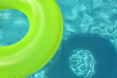 Bright inflatable ring floating in swimming pool on sunny day. Space for text