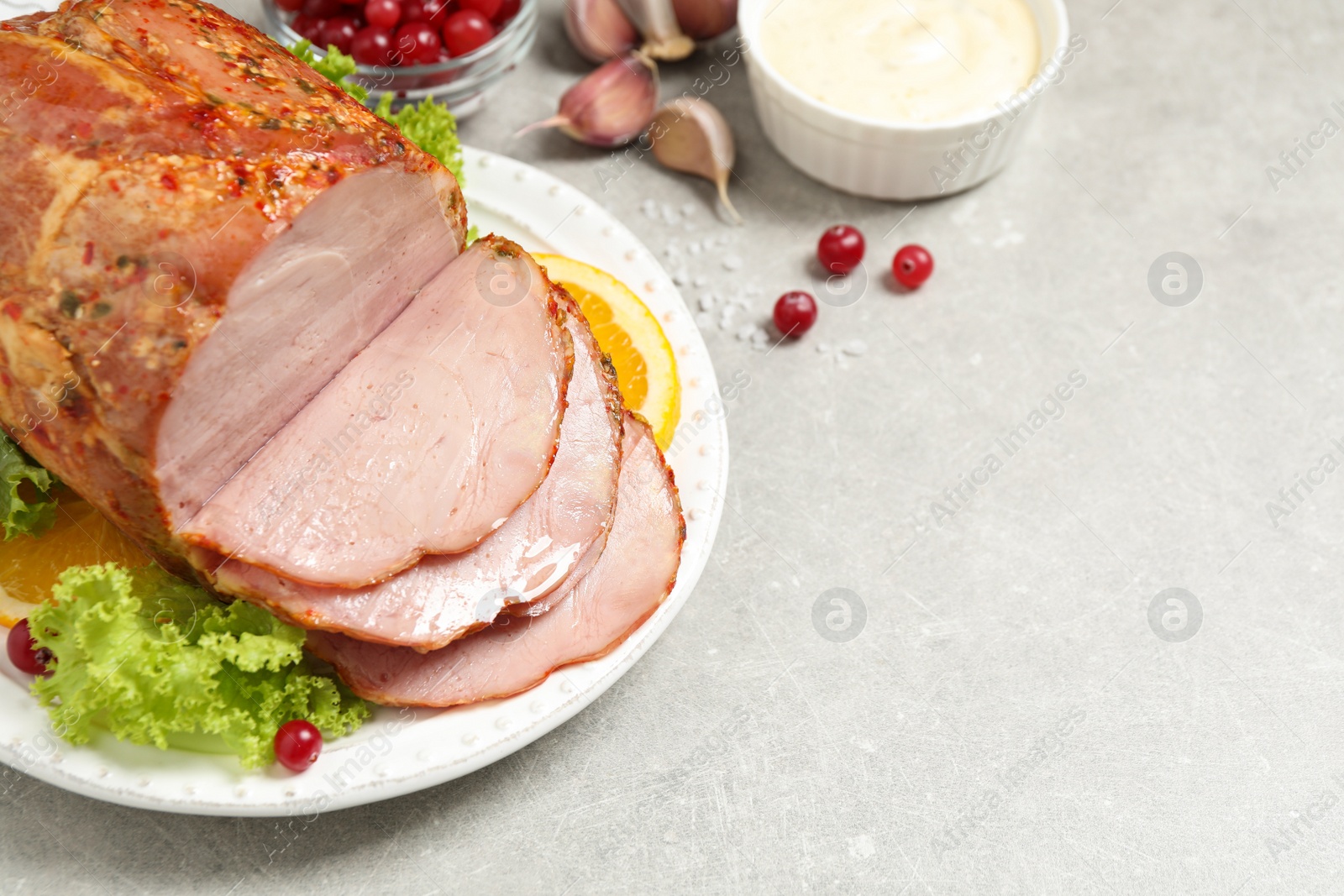 Photo of Delicious ham served with garnish on grey table, above view. Space for text