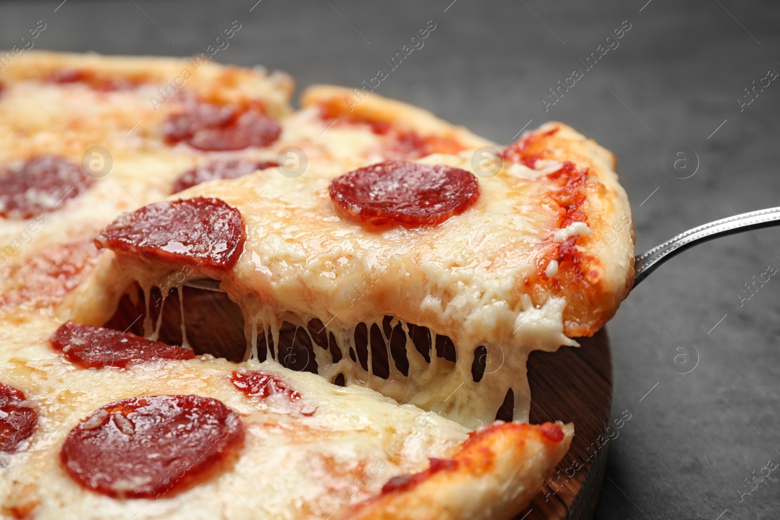 Photo of Taking slice of tasty pepperoni pizza on table, closeup