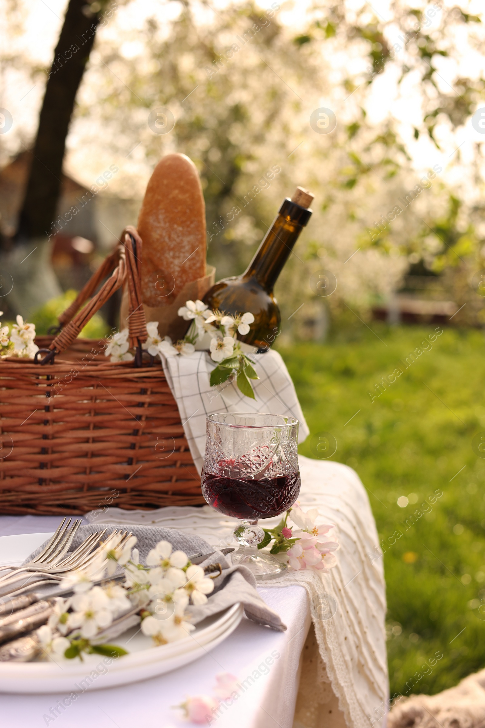 Photo of Stylish table setting with beautiful spring flowers and wine in garden