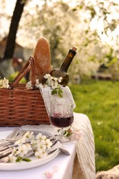 Stylish table setting with beautiful spring flowers and wine in garden