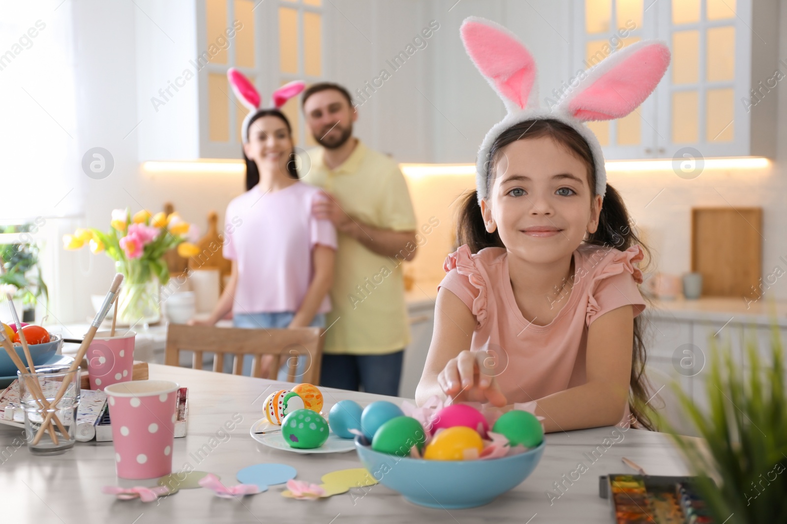 Photo of Cute little child painting Easter eggs at table in kitchen