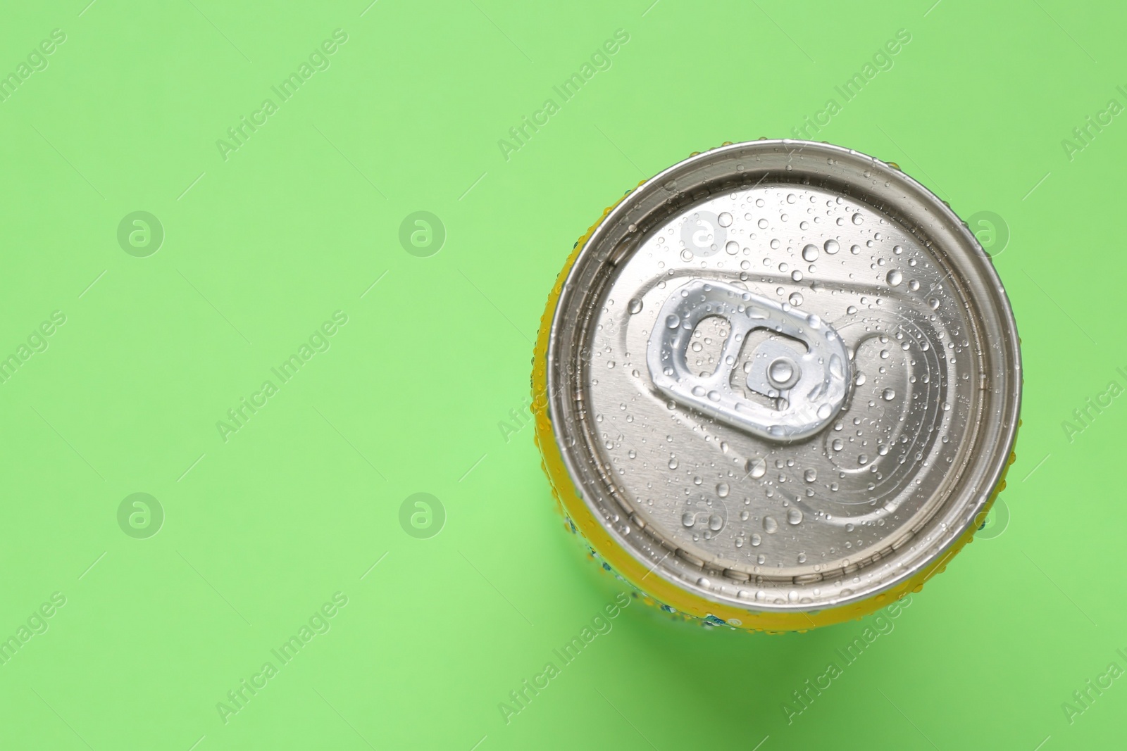 Photo of Energy drink in wet can on green background, top view. Space for text