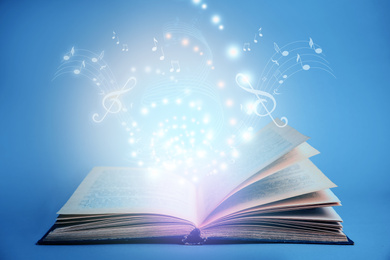 Image of Symphony shining with musical notes from open book on blue background 