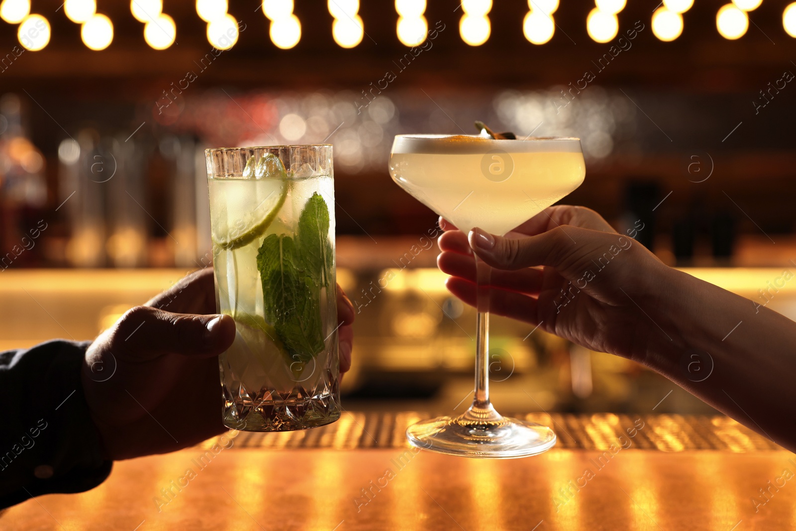 Photo of People holding glasses with fresh cocktails at bar counter, closeup