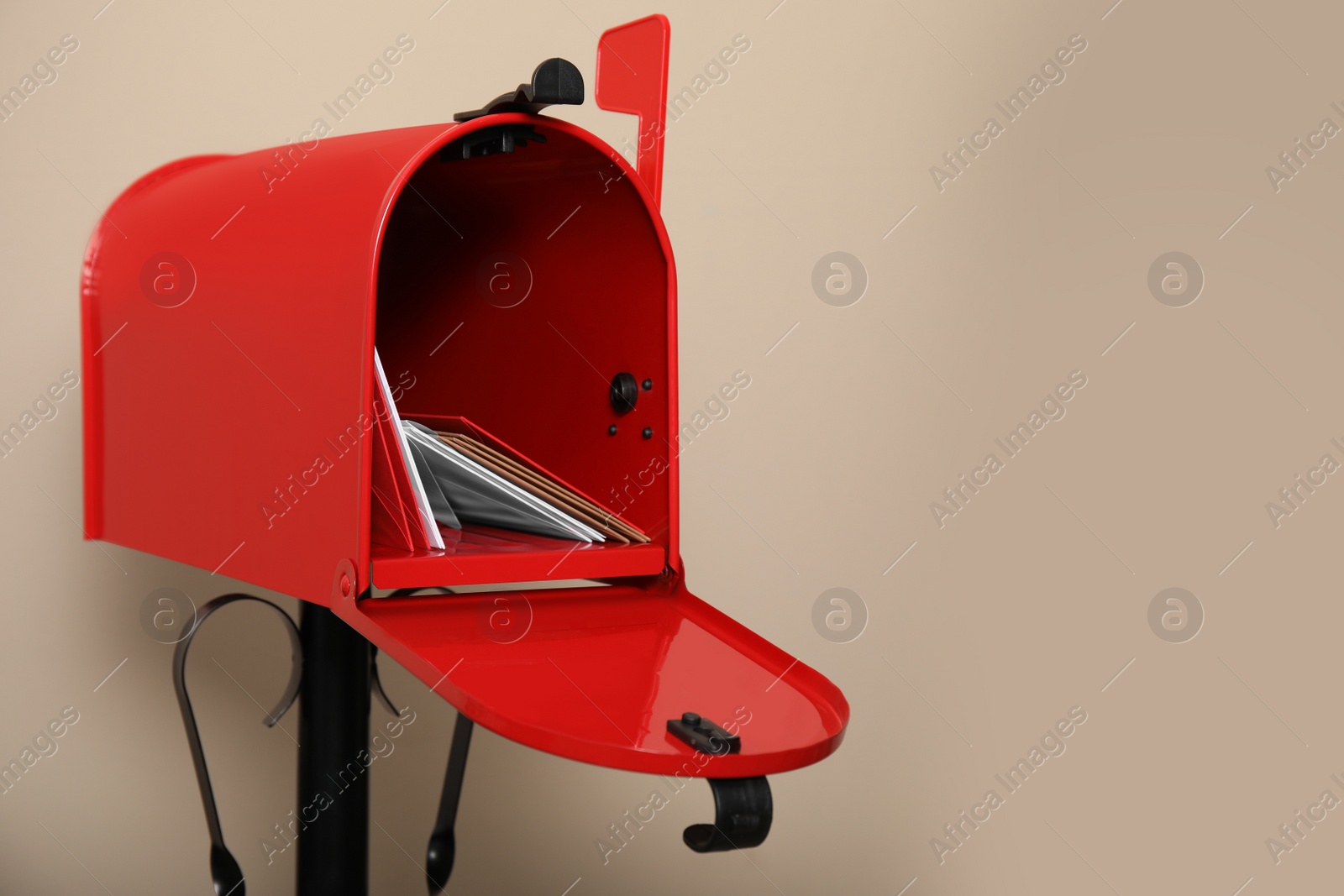 Photo of Open red letter box with envelopes against beige background. Space for text