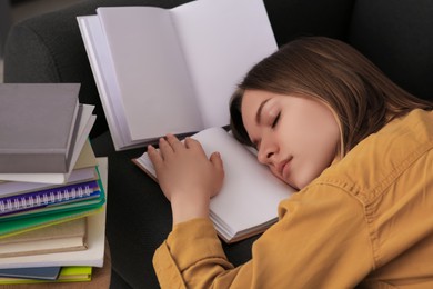 Young tired woman sleeping near books on couch