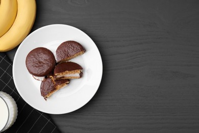 Photo of Tasty sweet choco pies, bananas and glass of milk on grey wooden table, flat lay. Space for text