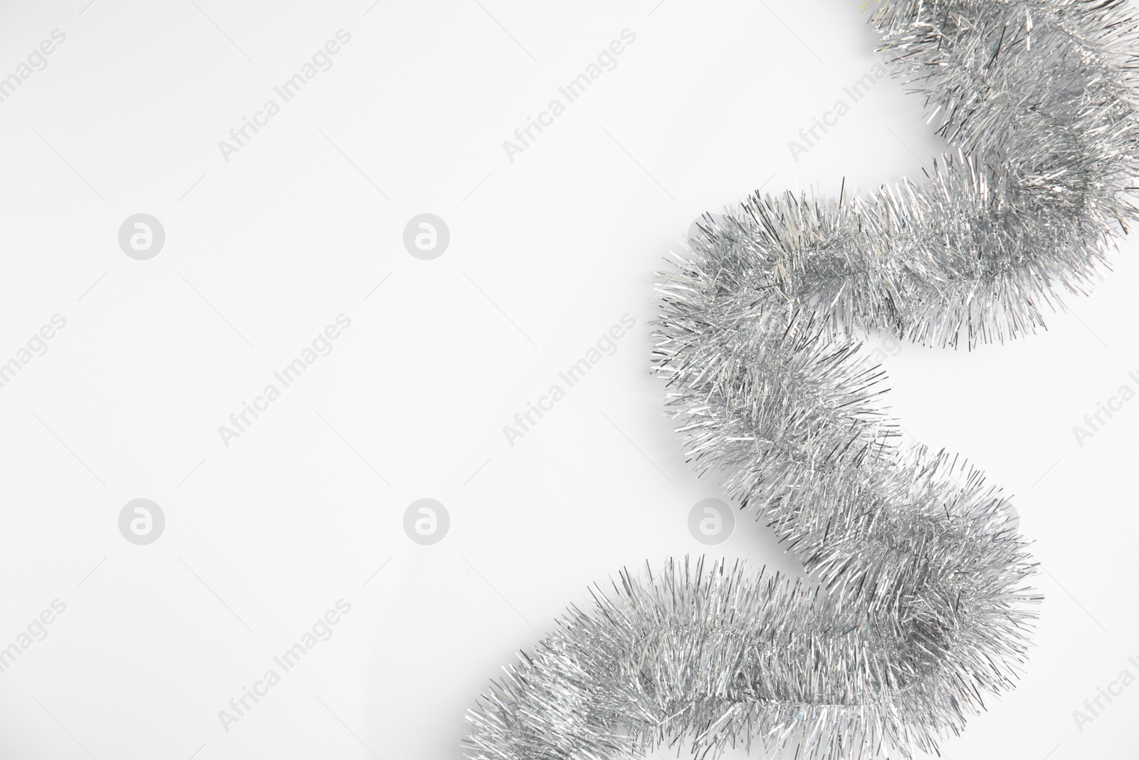 Photo of Silver tinsel on white background, top view. Space for text
