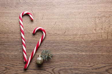 Photo of Candy canes and Christmas decor on wooden background, flat lay with space for text