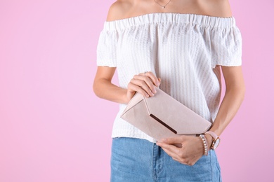 Young woman in stylish outfit with purse on color background, closeup