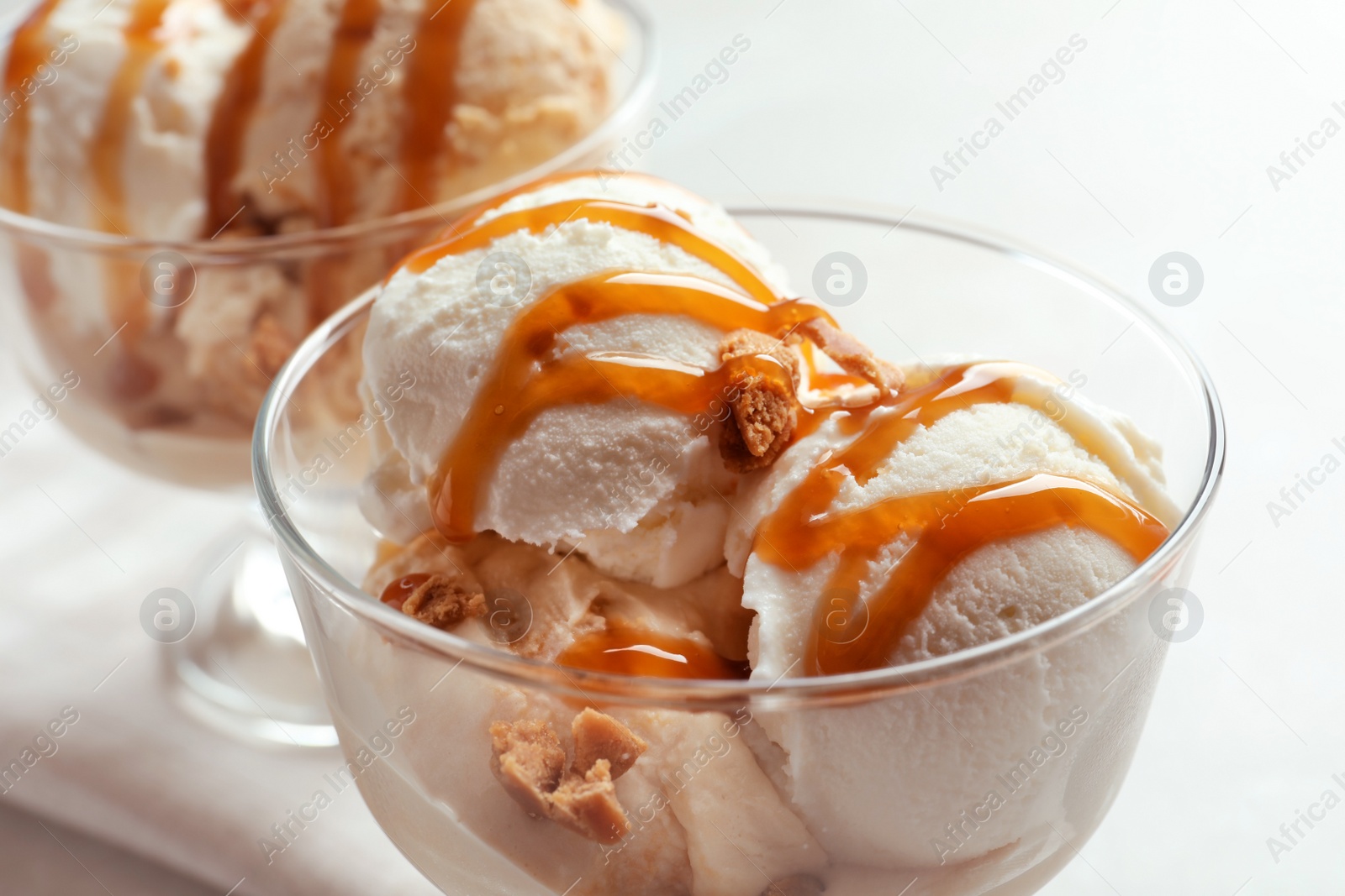 Photo of Bowls with caramel ice cream on light background, closeup