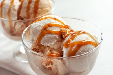 Bowls with caramel ice cream on light background, closeup