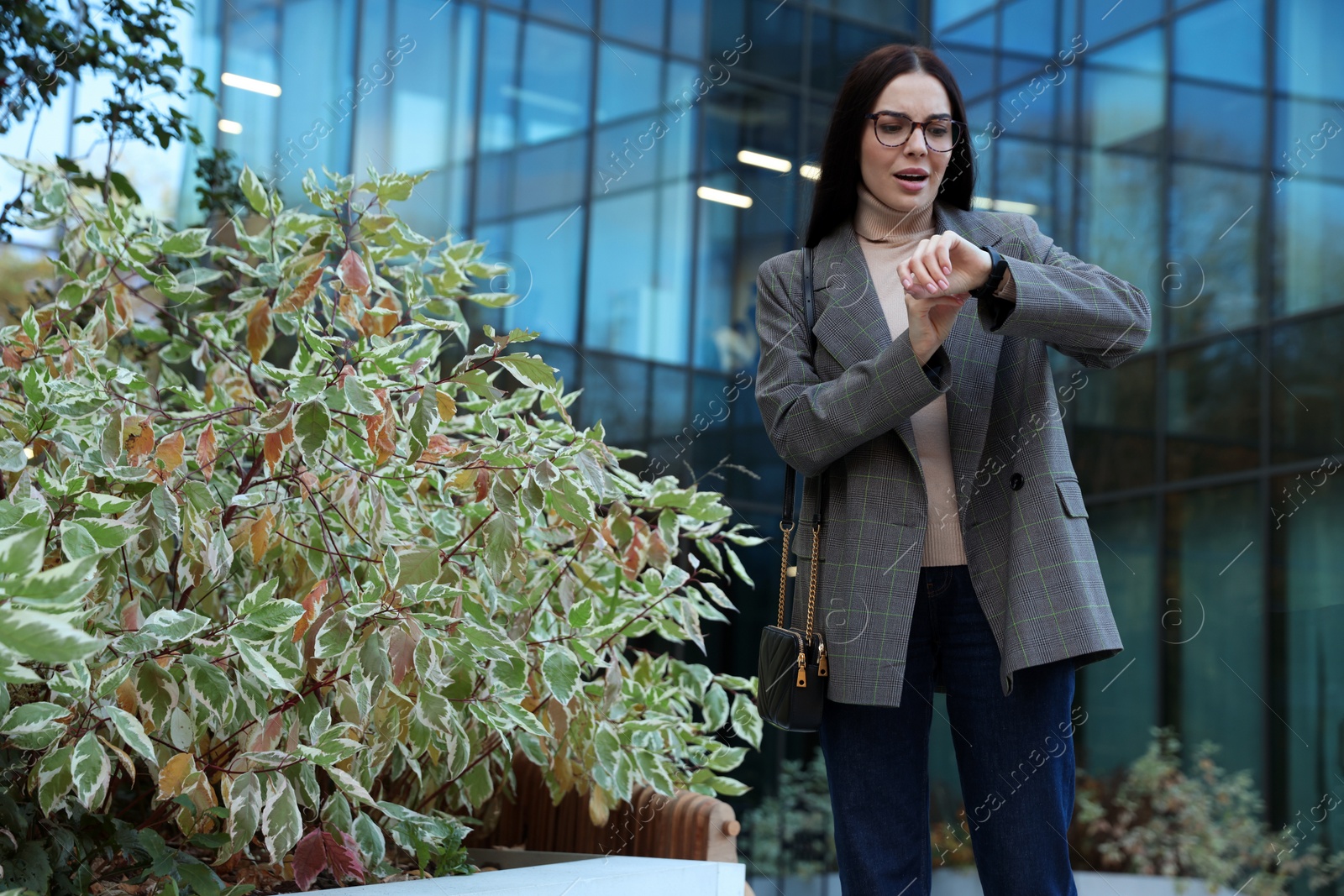 Photo of Emotional woman checking time on watch outdoors. Being late concept