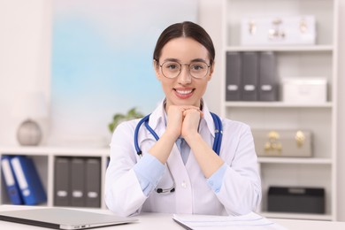 Photo of Medical consultant with glasses and stethoscope at table in clinic