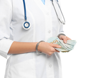 Doctor in handcuffs with bribe on white background, closeup. Corrupted medicine