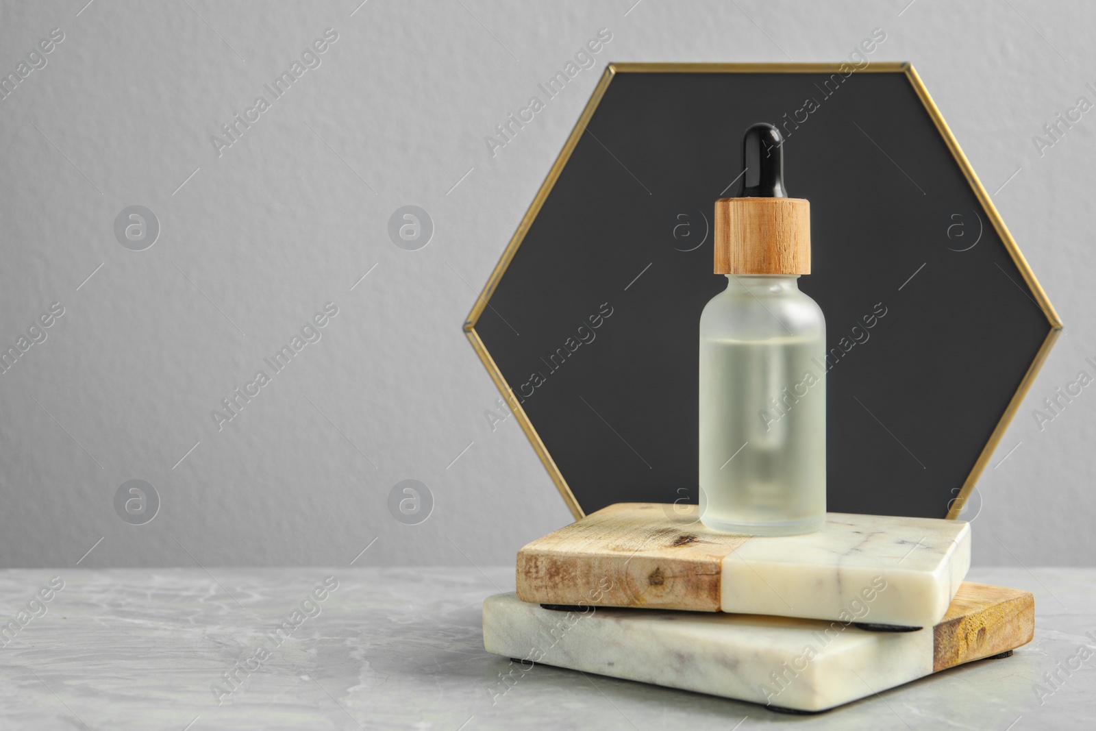 Photo of Bottle of face serum with marble boards on table against grey background. Space for text