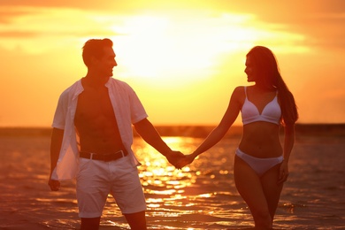 Photo of Happy young couple spending time together on sea beach at sunset