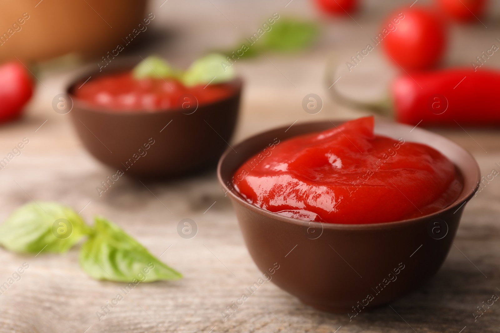 Photo of Bowls with spicy chili sauce on wooden table