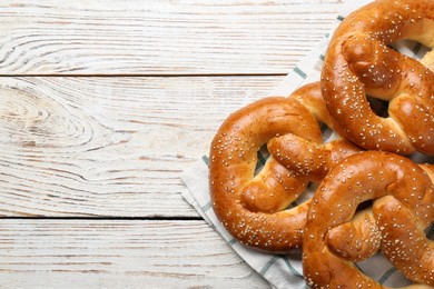 Photo of Delicious pretzels with sesame seeds on white wooden table, top view. Space for text