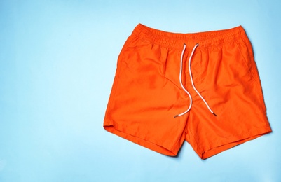 Stylish male swim trunks on color background, top view with space for text. Beach object