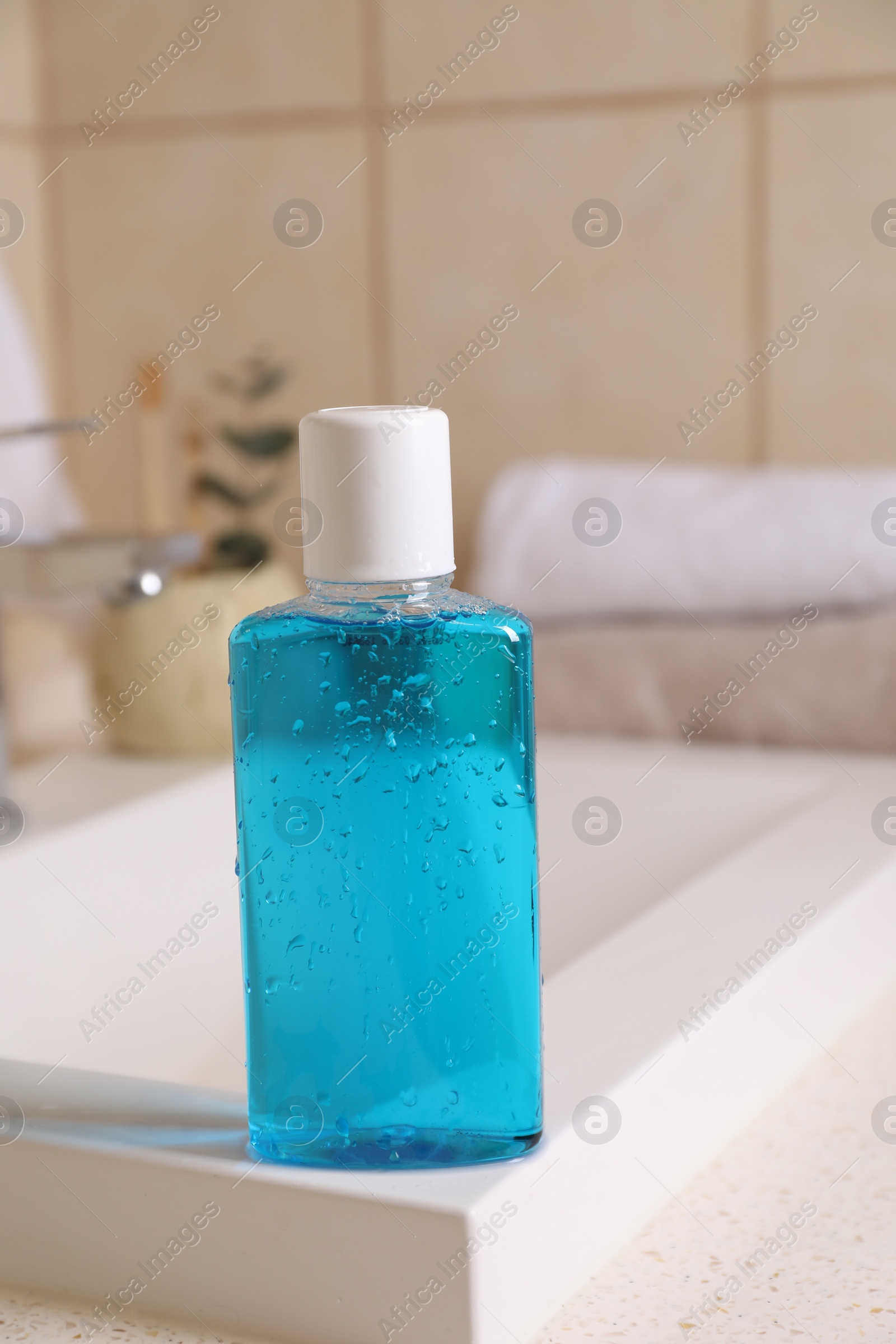 Photo of Fresh mouthwash in bottle on sink in bathroom, closeup