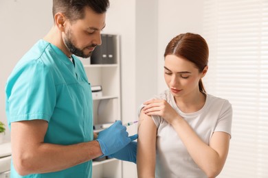 Doctor giving hepatitis vaccine to patient in clinic